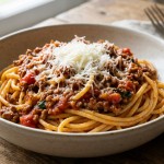 savourez un délice italien incontournable avec nos spaghetti bolognaise authentiques, généreusement nappés de fromage râpé traditionnel pour un goût riche et savoureux.