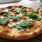 savourez notre pizza maison gourmande garnie de jambon savoureux, d'épinards frais et de chèvre onctueux, pour un délice équilibré et plein de saveurs.
